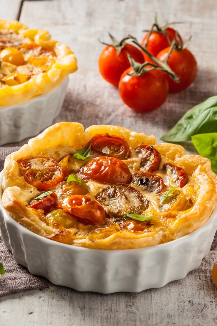 Quiche with cherry tomatoes on a rustic wooden table.