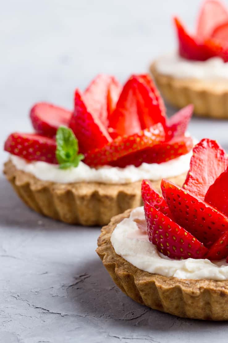 Strawberry vanilla cream cheese tarts over light gray background